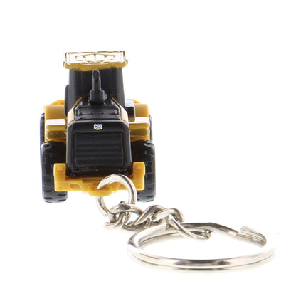 A miniature yellow and black toy wheel loader keychain with a metal key ring attached, shown on a plain white background.