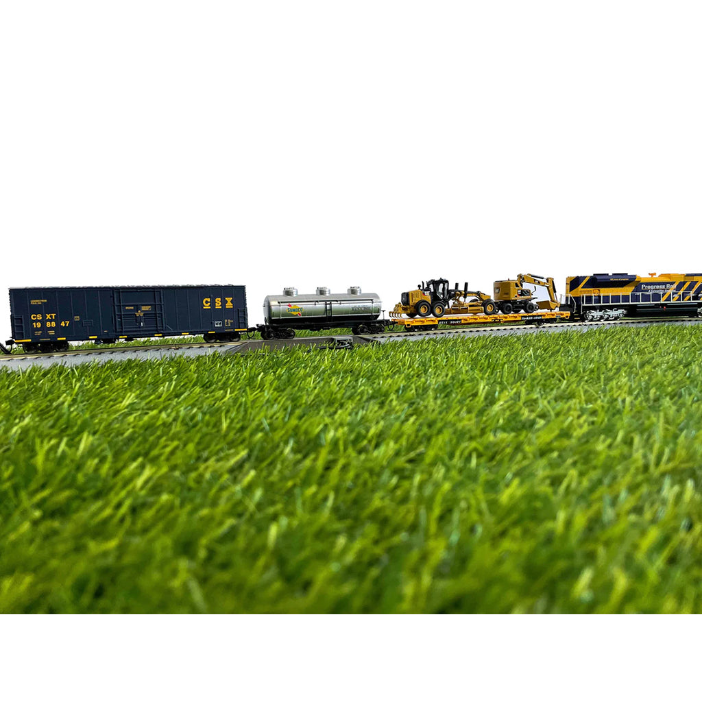 Model trains on a track with grass in the foreground