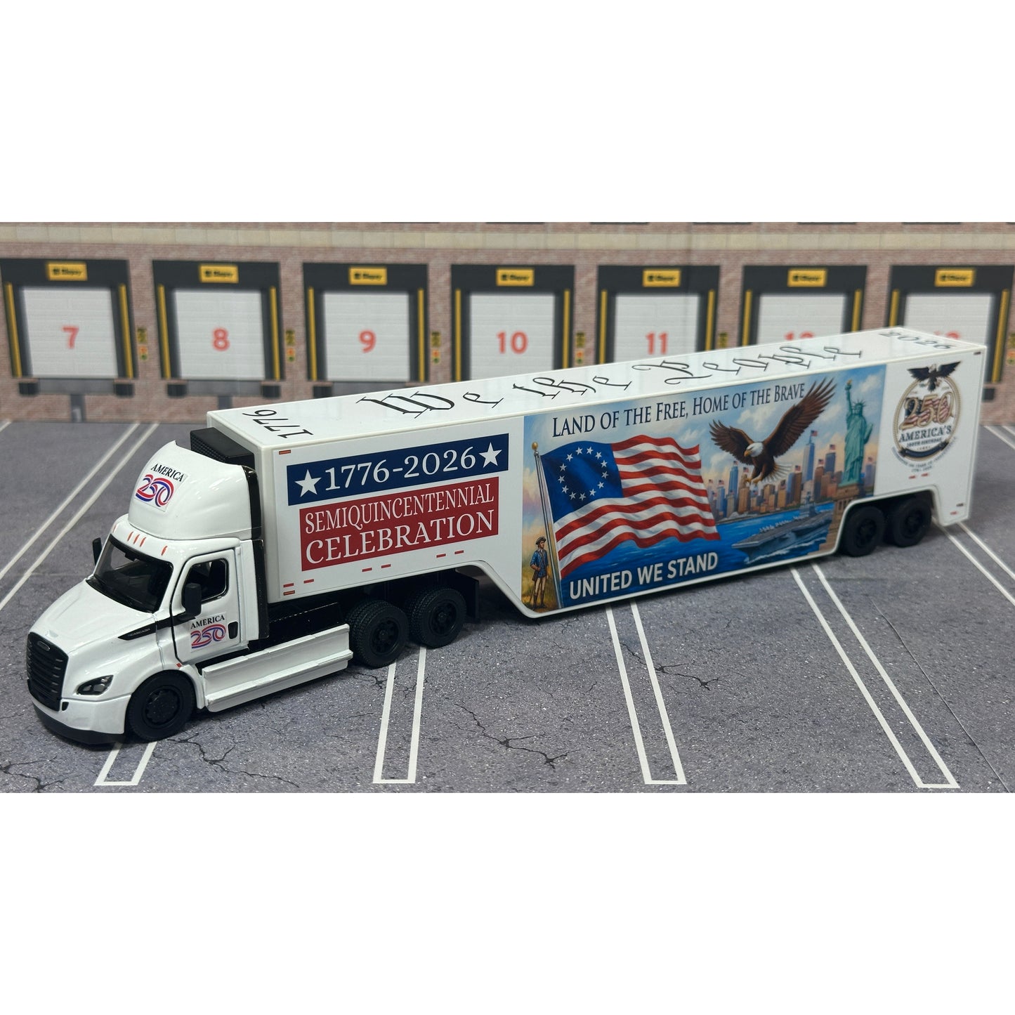 A diecast model of a Freightliner Cascadia semi-truck parked in a simulated parking lot. The trailer features a detailed historical design celebrating the United States' 250th anniversary with 'We the People' written on the top, alongside an American flag, eagle, and city skyline graphic with the text 'Land of the Free Home of the Brave' and 'United We Stand'.
