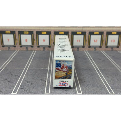 A diecast model of a Freightliner Cascadia semi-truck parked in a simulated parking lot. The trailer features a detailed historical design celebrating the United States' 250th anniversary with 'We the People' written on the top, alongside an American flag, eagle, and city skyline graphic with the text 'Land of the Free Home of the Brave' and 'United We Stand'.
