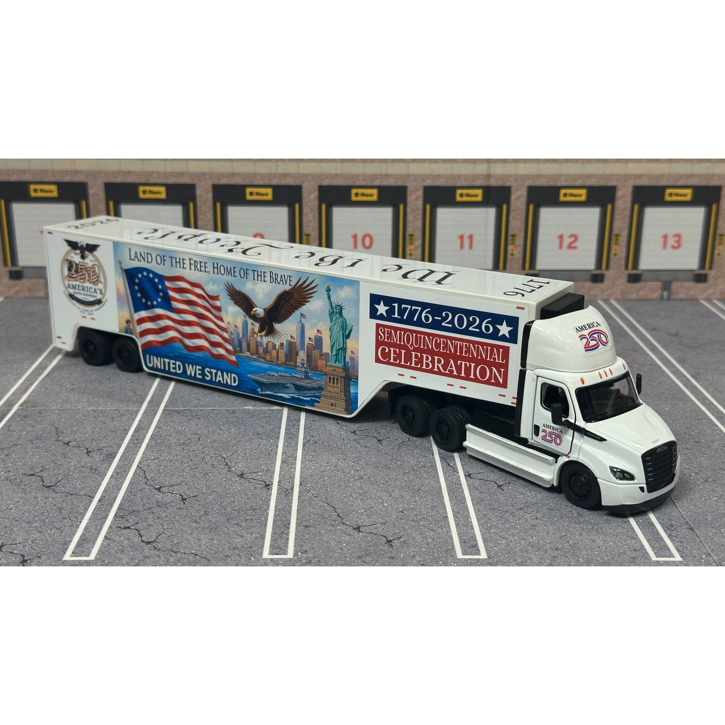 A diecast model of a Freightliner Cascadia semi-truck parked in a simulated parking lot. The trailer features a detailed historical design celebrating the United States' 250th anniversary with 'We the People' written on the top, alongside an American flag, eagle, and city skyline graphic with the text 'Land of the Free Home of the Brave' and 'United We Stand'.