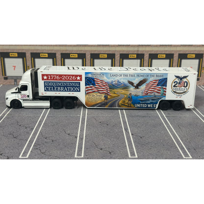 A diecast model of a Freightliner Cascadia semi-truck parked in a simulated parking lot. The trailer features a detailed historical design celebrating the United States' 250th anniversary with 'We the People' written on the top, alongside an American flag, eagle, and city skyline graphic with the text 'Land of the Free Home of the Brave' and 'United We Stand'.