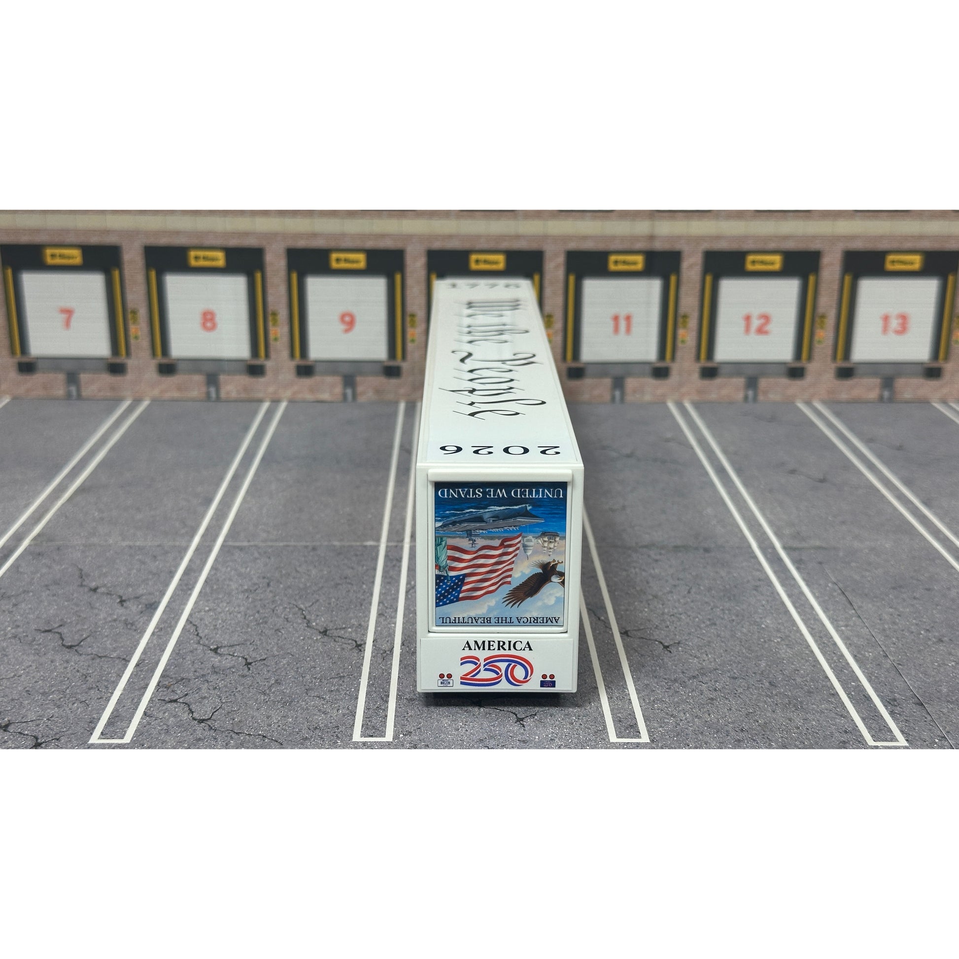 A diecast model of a Freightliner Cascadia semi-truck parked in a simulated parking lot. The trailer features a detailed historical design celebrating the United States' 250th anniversary with 'We the People' written on the top, alongside an American flag, eagle, and city skyline graphic with the text 'Land of the Free Home of the Brave' and 'United We Stand'.