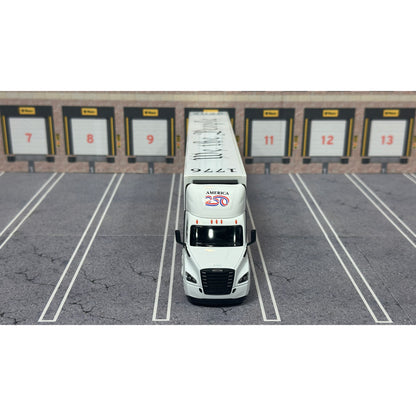 A diecast model of a Freightliner Cascadia semi-truck parked in a simulated parking lot. The trailer features a detailed historical design celebrating the United States' 250th anniversary with 'We the People' written on the top, alongside an American flag, eagle, and city skyline graphic with the text 'Land of the Free Home of the Brave' and 'United We Stand'.