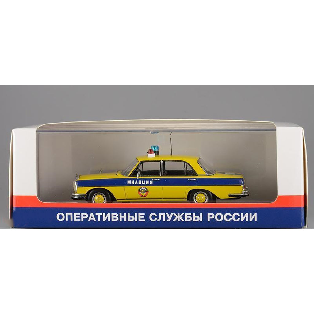 A 1975 Mercedes-Benz W108 'Moscow Police' model car in yellow, blue, and white colors with black wheels and interior in window box packaging.