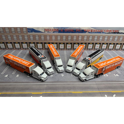 Model trucks with orange and white trailers on a parking lot with a building in the background