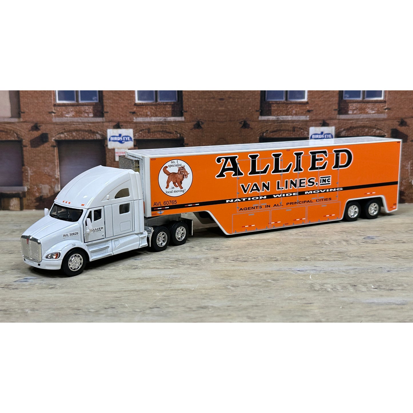 Model truck with 'Allied Van Lines' branding in front of a brick building.