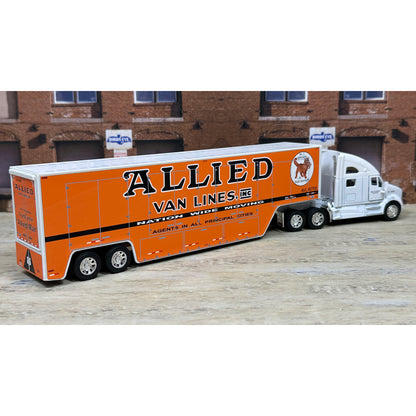 Model of a semi-truck with 'Allied Van Lines' branding in front of a brick building.