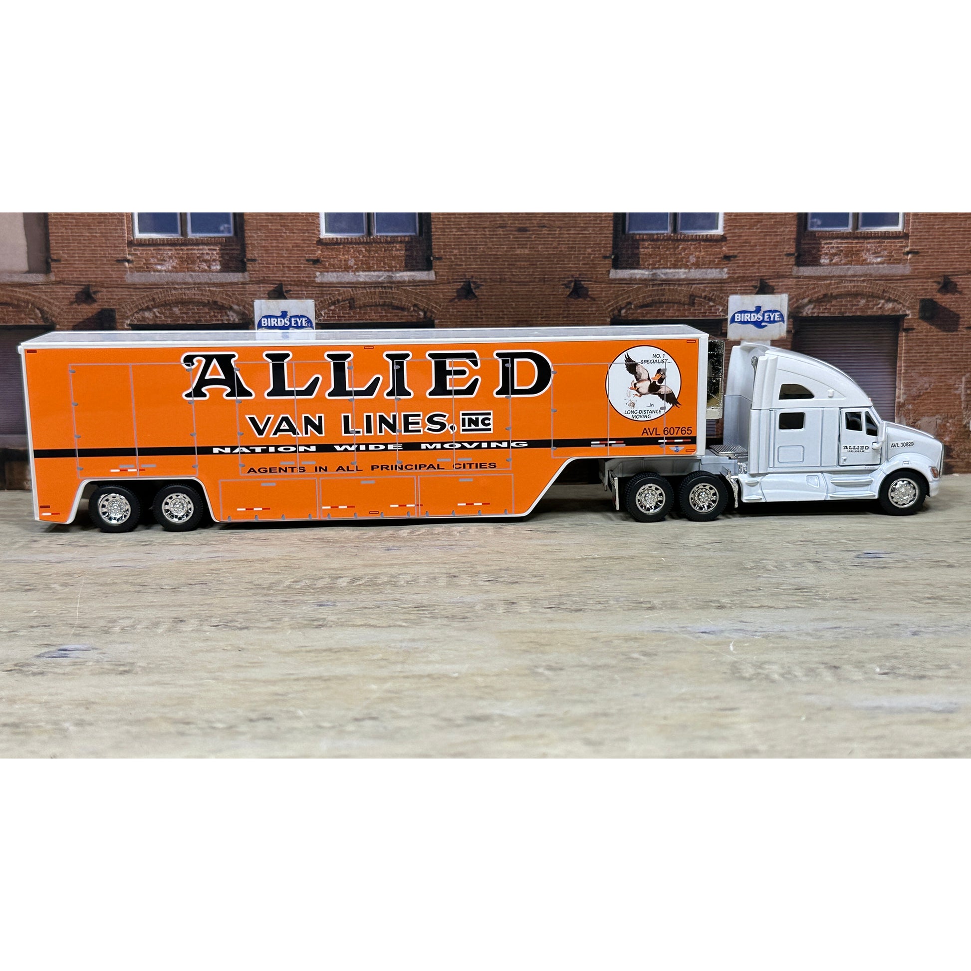 Model truck with 'Allied Van Lines' branding in front of a brick building.