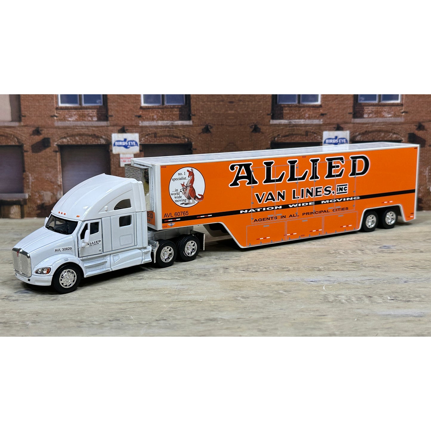 Model truck with 'Allied Van Lines' trailer in front of a brick building.