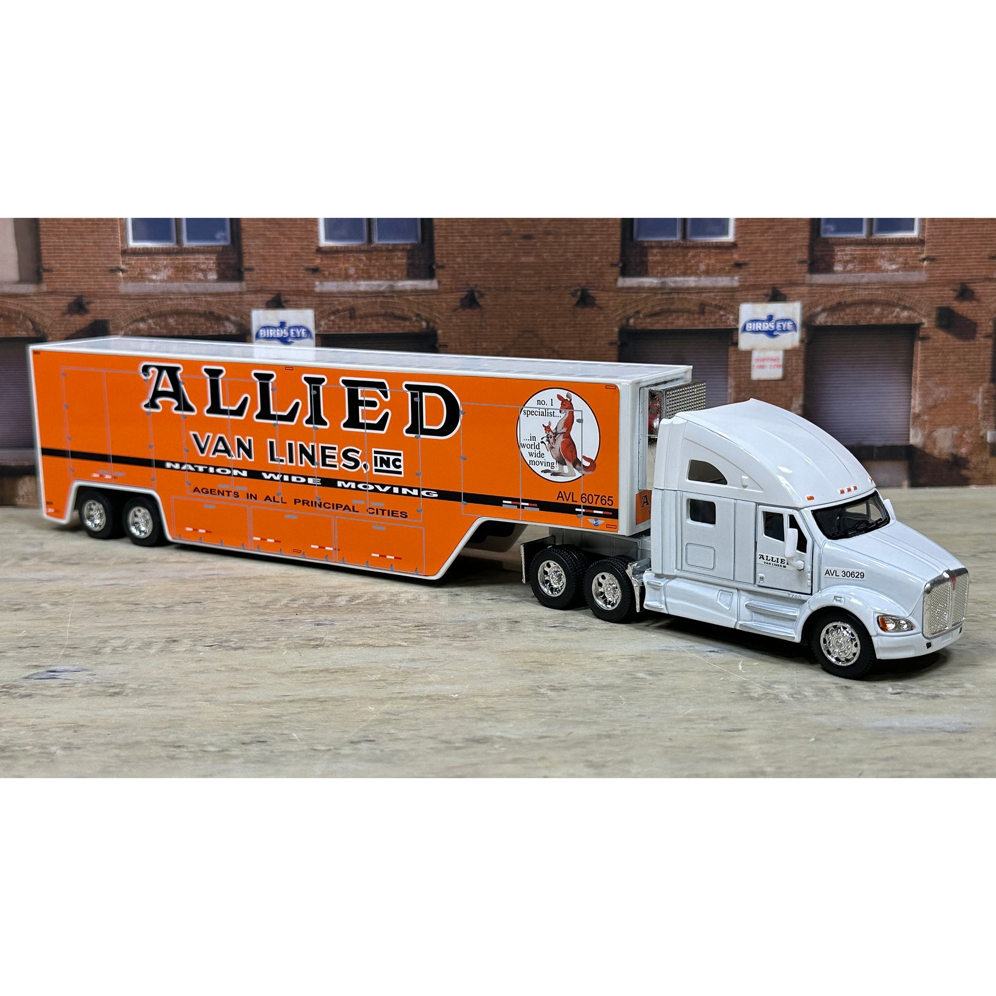 Model truck with 'Allied Van Lines, Inc.' branding in front of a brick building.