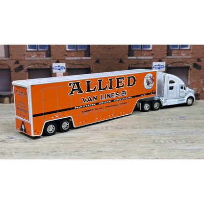 Model of a semi-truck with an orange trailer labeled 'Allied Van Lines' in front of a brick building.