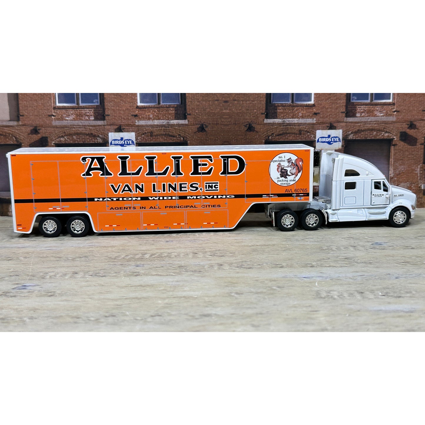 Model truck with 'Allied Van Lines' branding in front of a brick building.