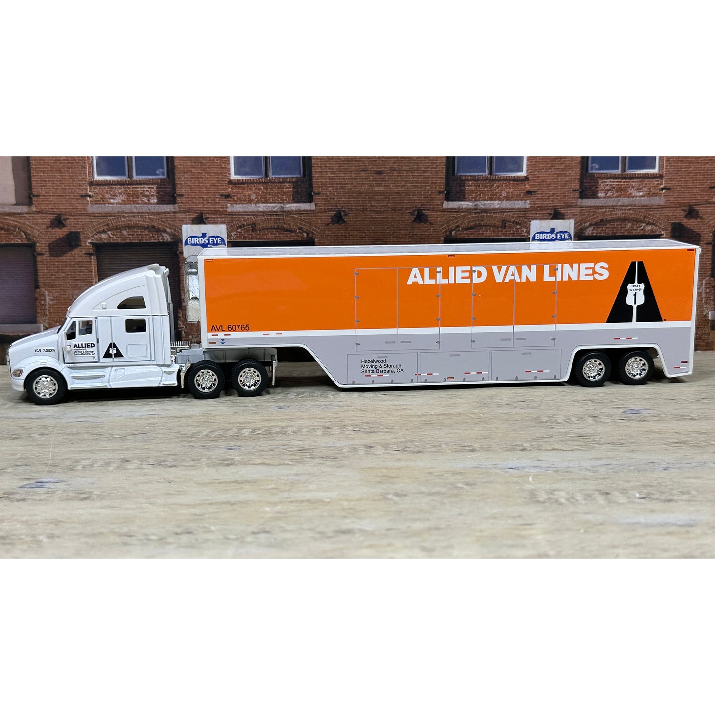 Model of an Allied Van Lines truck in front of a brick building.