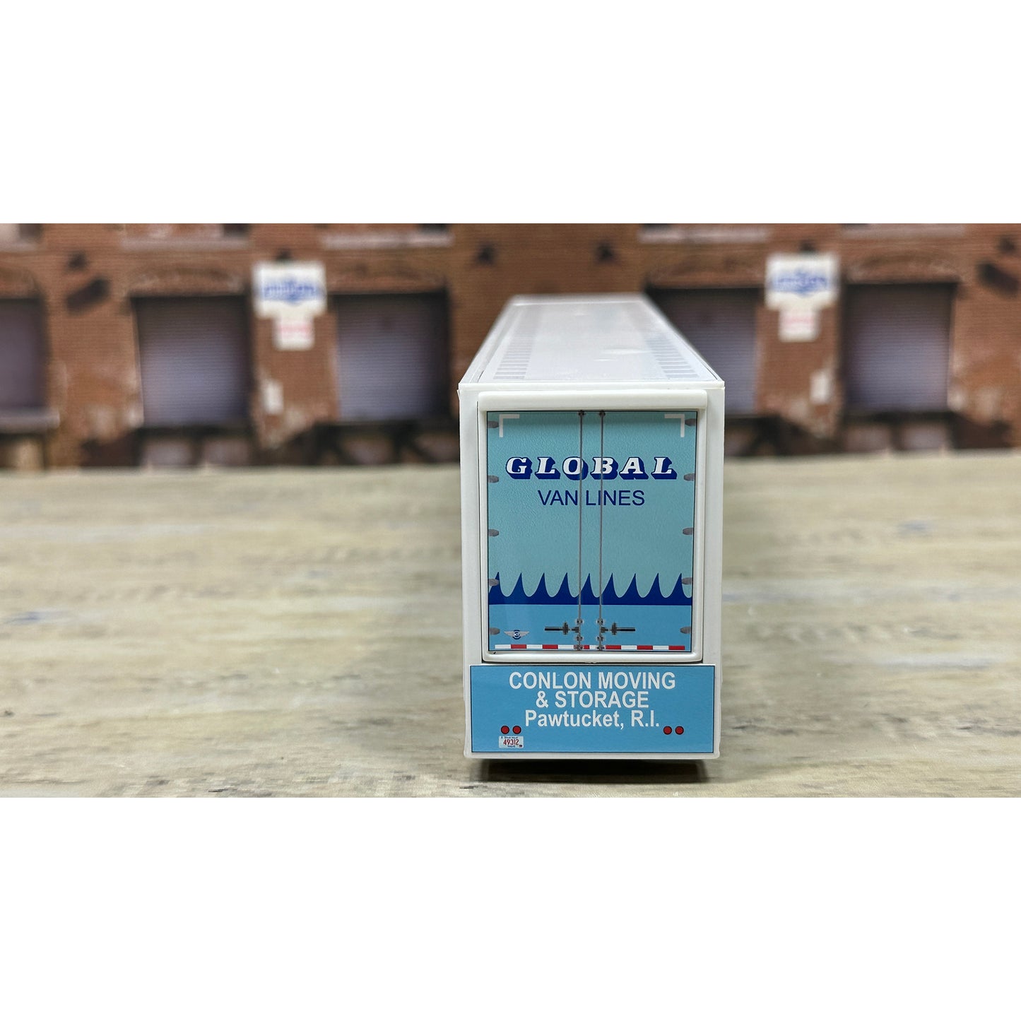 Model of a moving van with 'Global Van Lines' branding on a wooden surface.