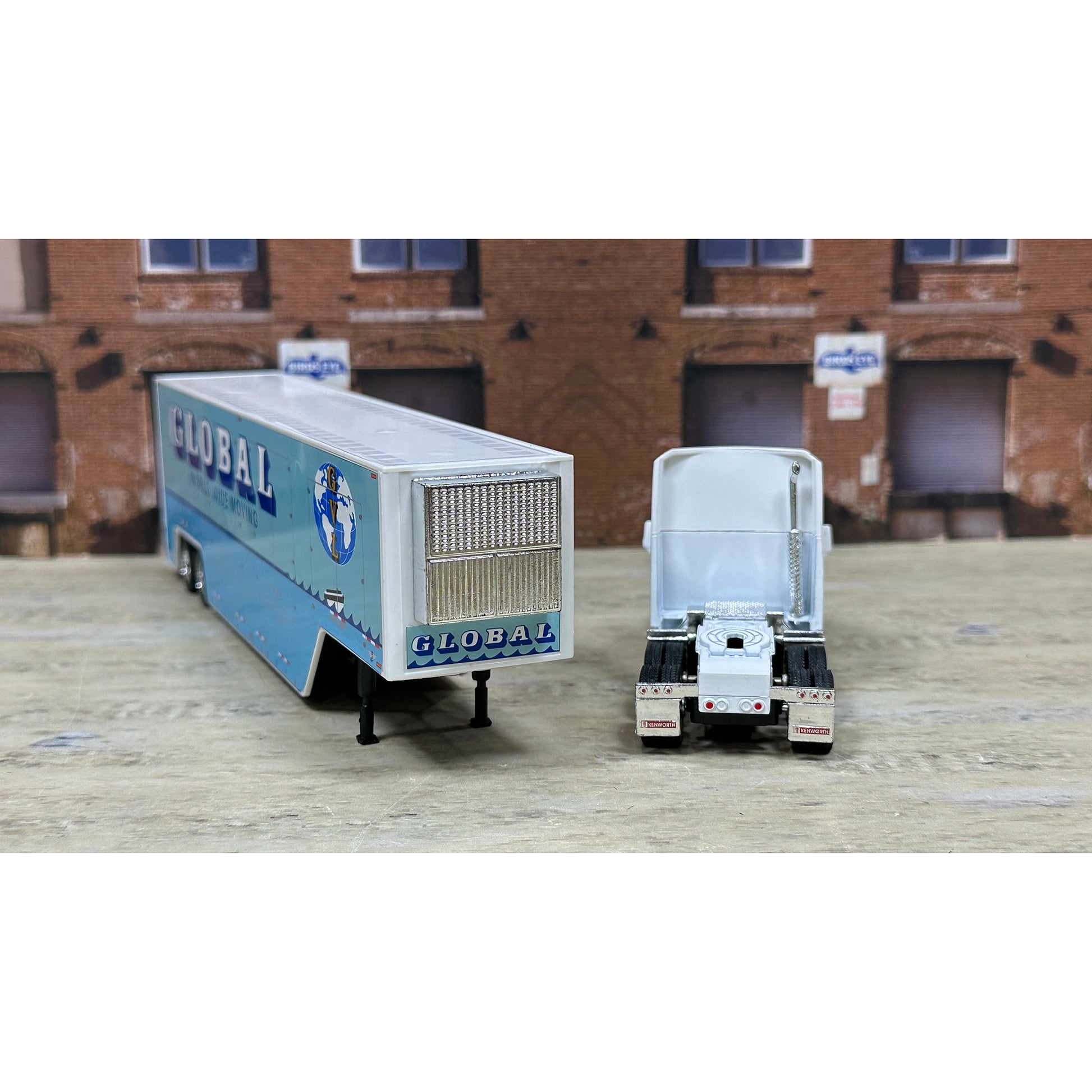 Model of a truck with 'GLOBAL' branding on a wooden surface with a brick building background.