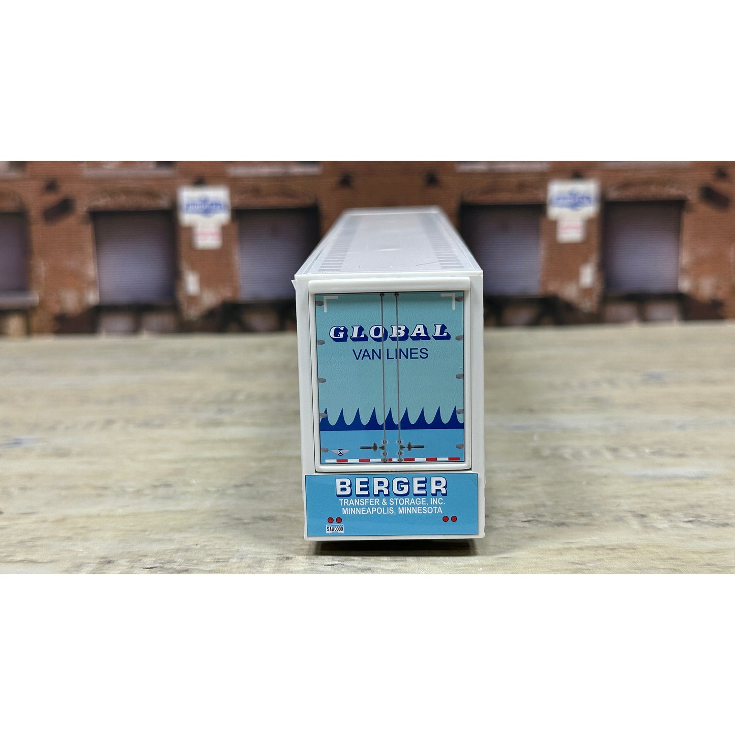 Model of a cargo container with 'Global Van Lines' branding on a wooden surface.